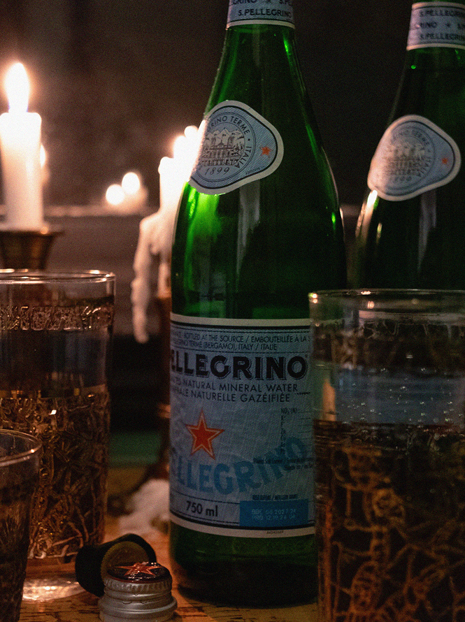 Nighttime in the kitchen with bottles and glasses leftover after a party.