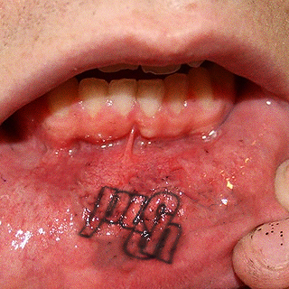 Man showing his inner lip tattoo.